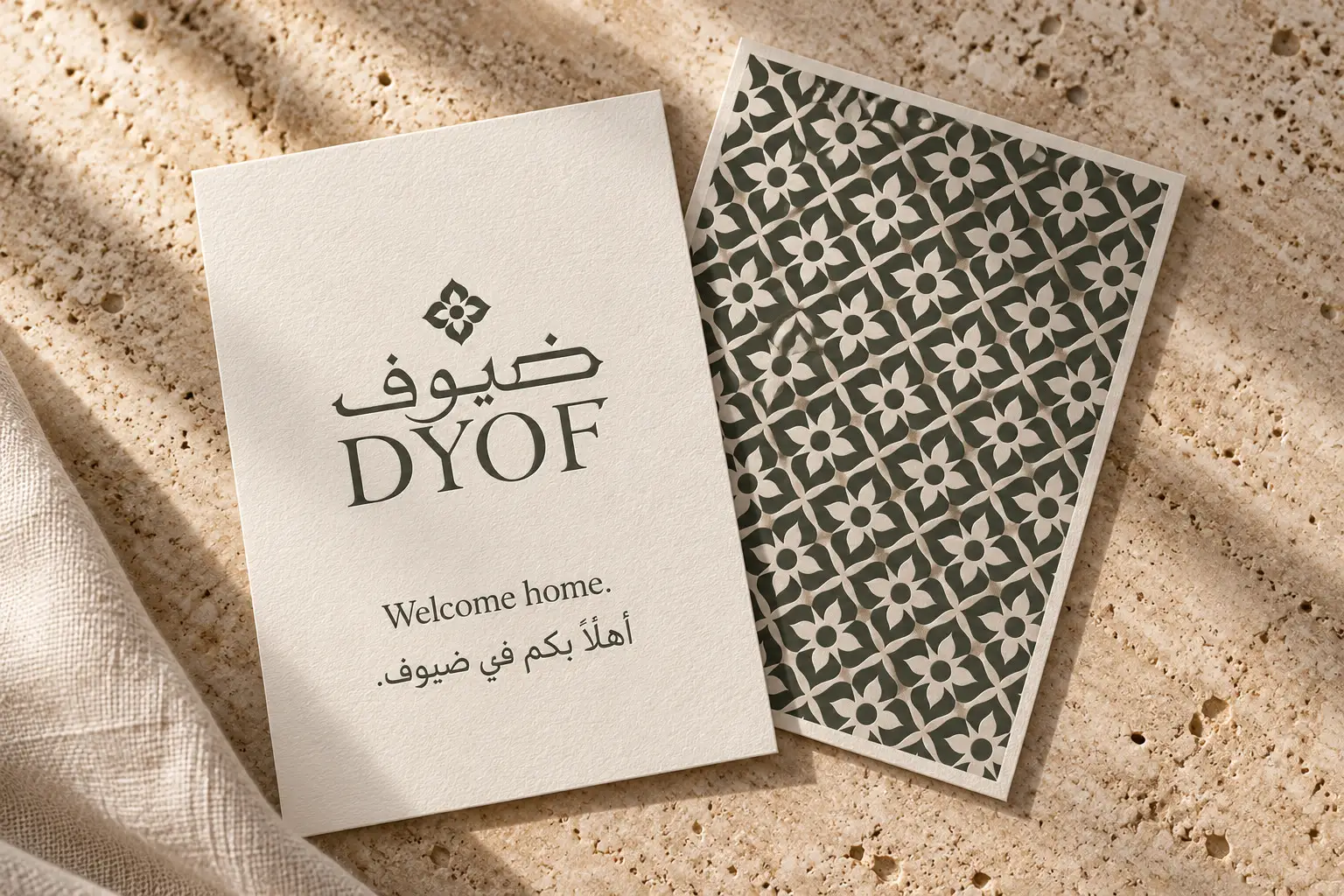 A DYOF welcome card beside a patterned card on warm travertine